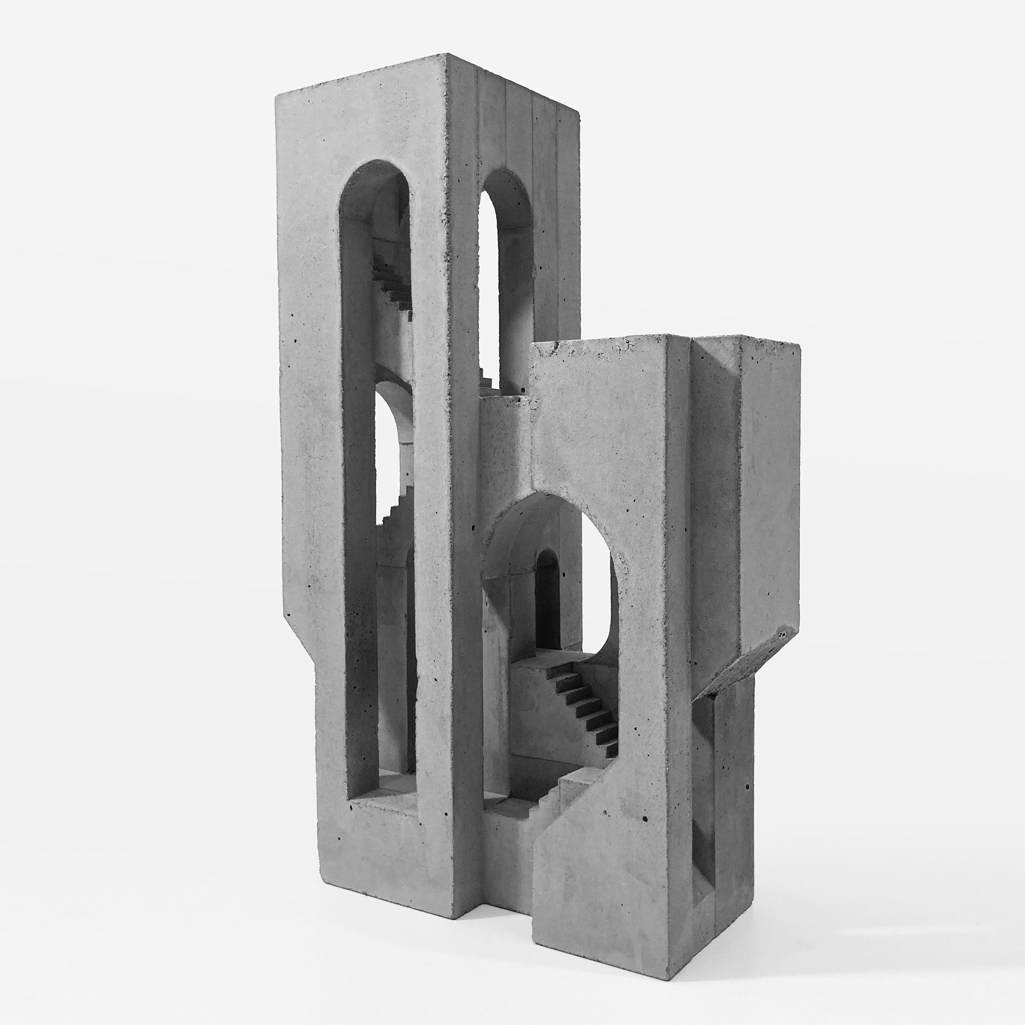 A gray concrete architectural sculpture with arch openings and stair-like recesses, photographed on a clean white studio background.