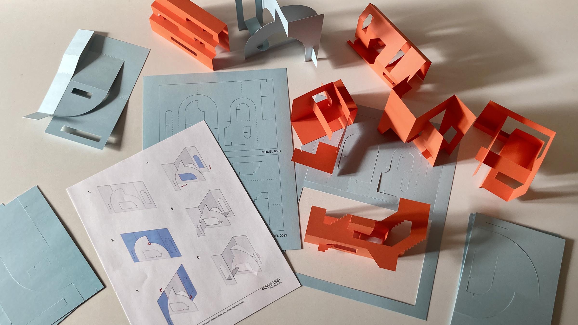 Construction set with building paper modules and blueprints on a light surface