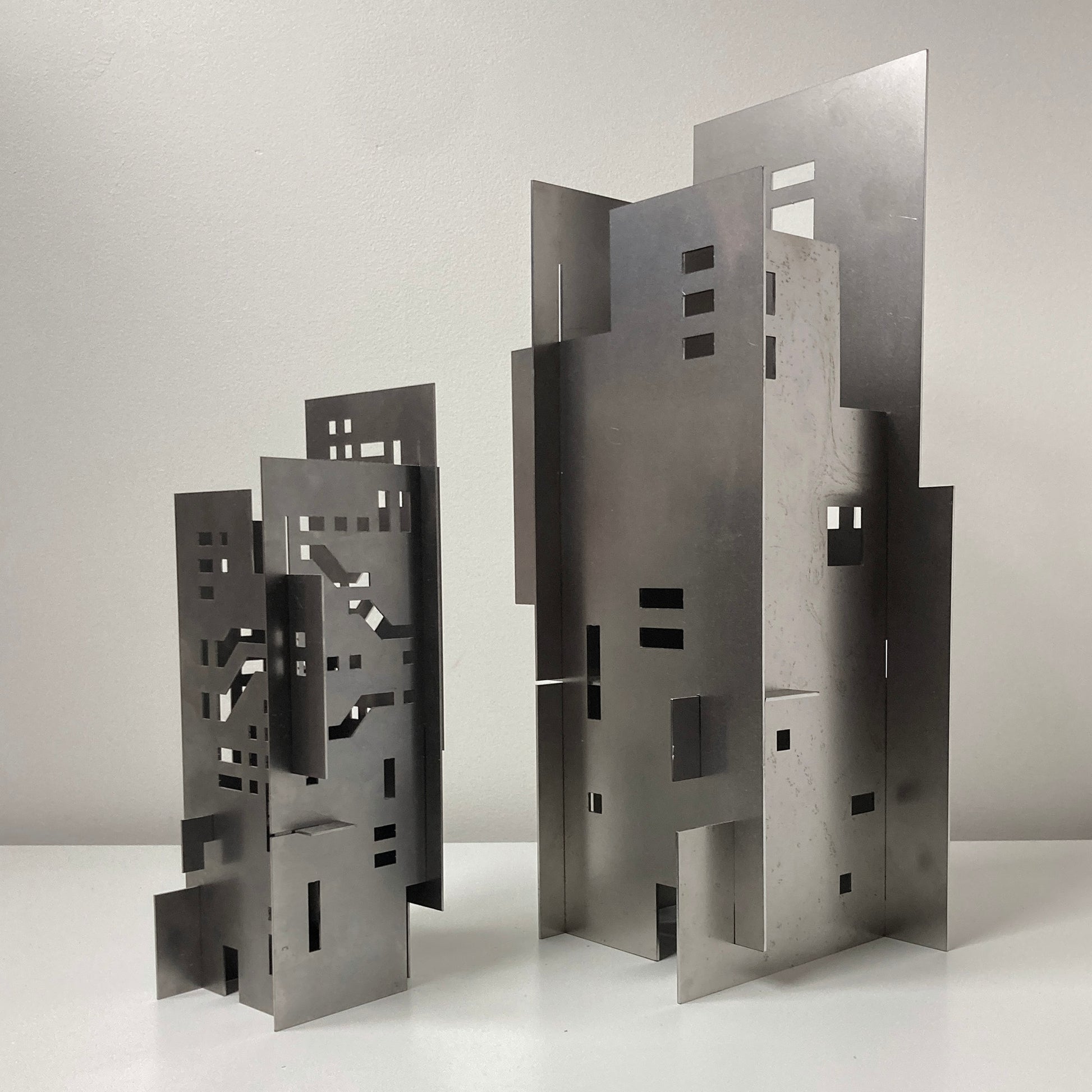 Modern architectural cityscape table lamp made from assembled sheet metal with geometric cutouts and layered skyscraper forms.
