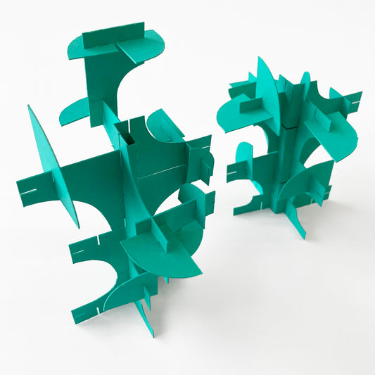 Green geometric paper tree sculptures on a white background