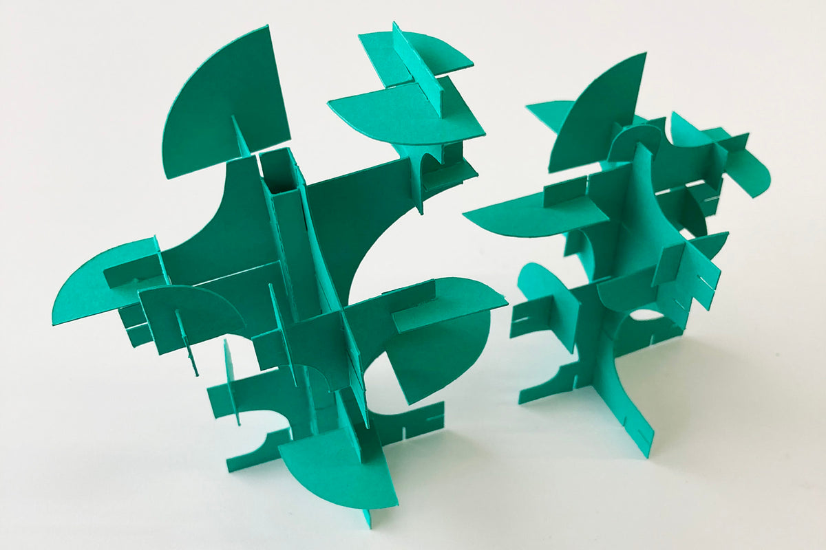 Two green paper models of trees on a white background