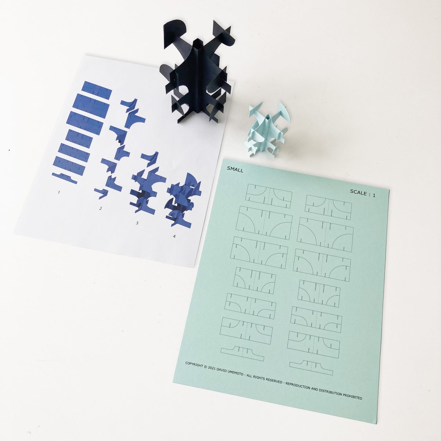 Puzzle paper tree pieces and design sheets on a white surface