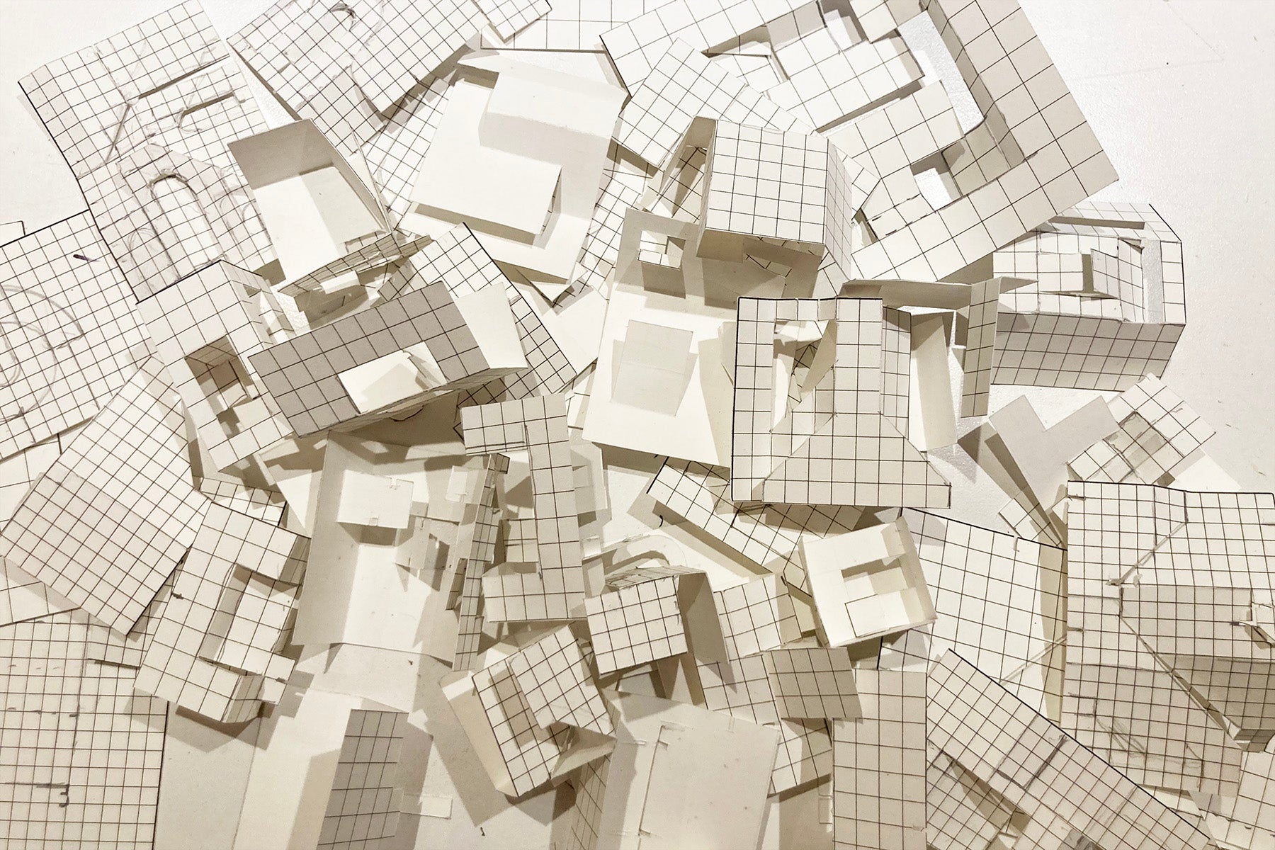 Scattered grid-patterned paper pieces on a white background