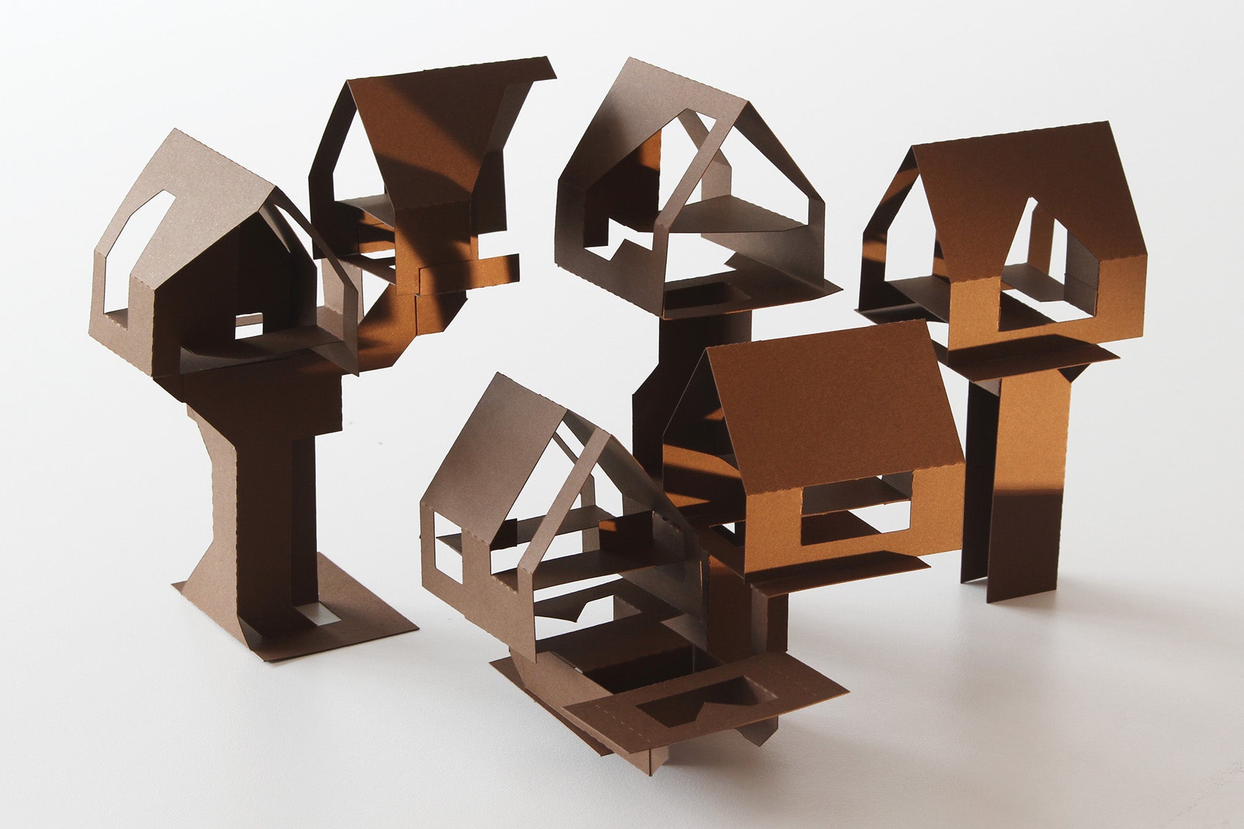 Set of cardstock paper cutout tree houses on a white surface
