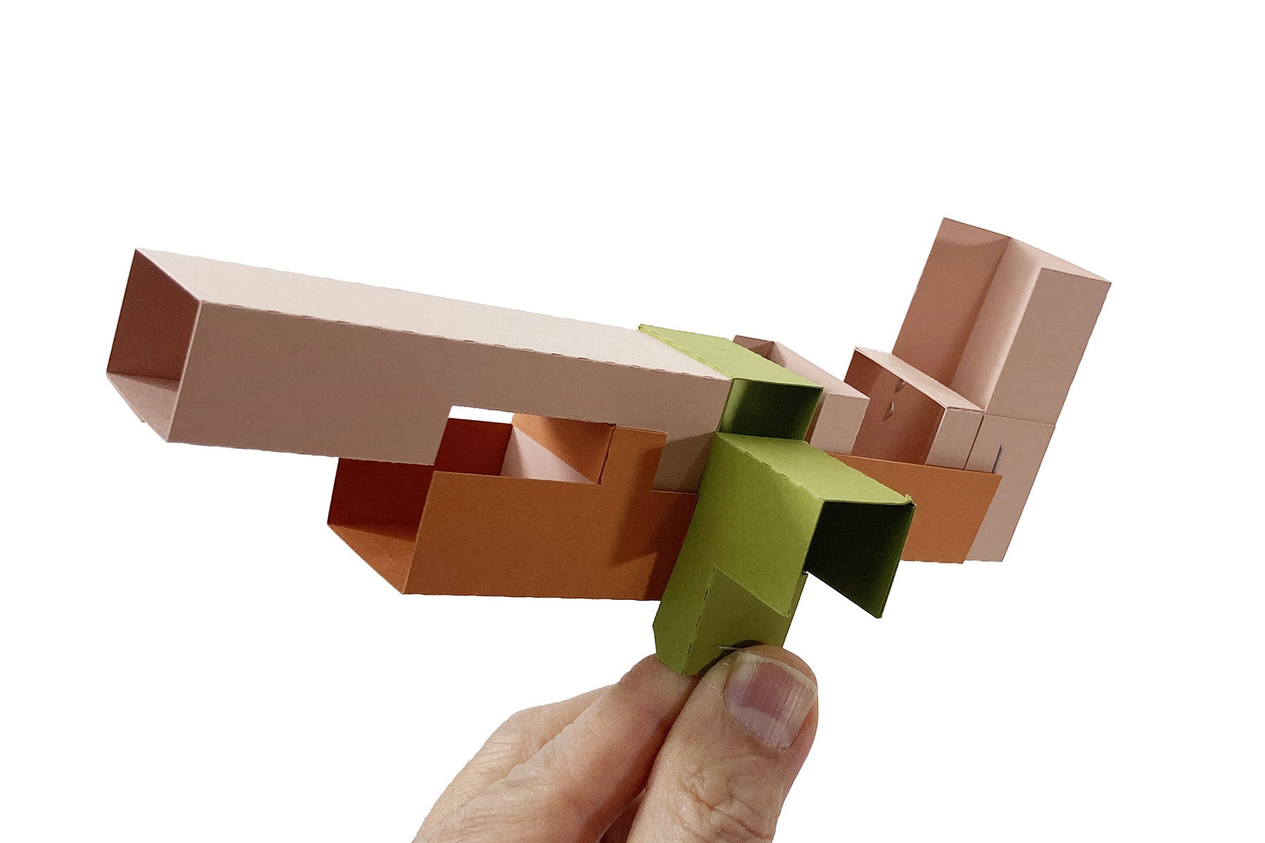 Hand holding colorful geometric cardboard creature made from interlocking pieces on a white background